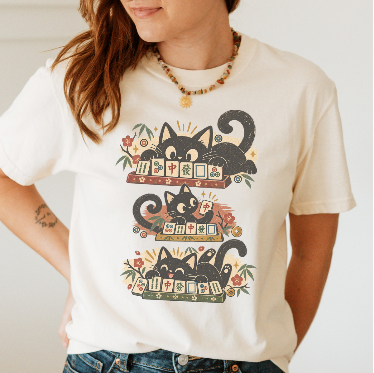 Retro Black Cats Mahjong Shirt in Ivory - worn by a woman, three black cats over a row of mahjong tiles with arched MAHJONG lettering