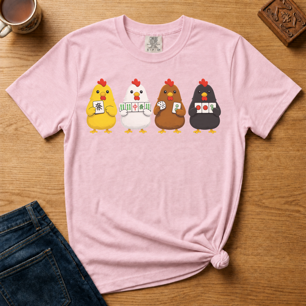 Mahjong Chickens Shirt in Blossom - four cartoon hens holding mahjong tiles on a pink Comfort Colors 1717 tee, flat lay