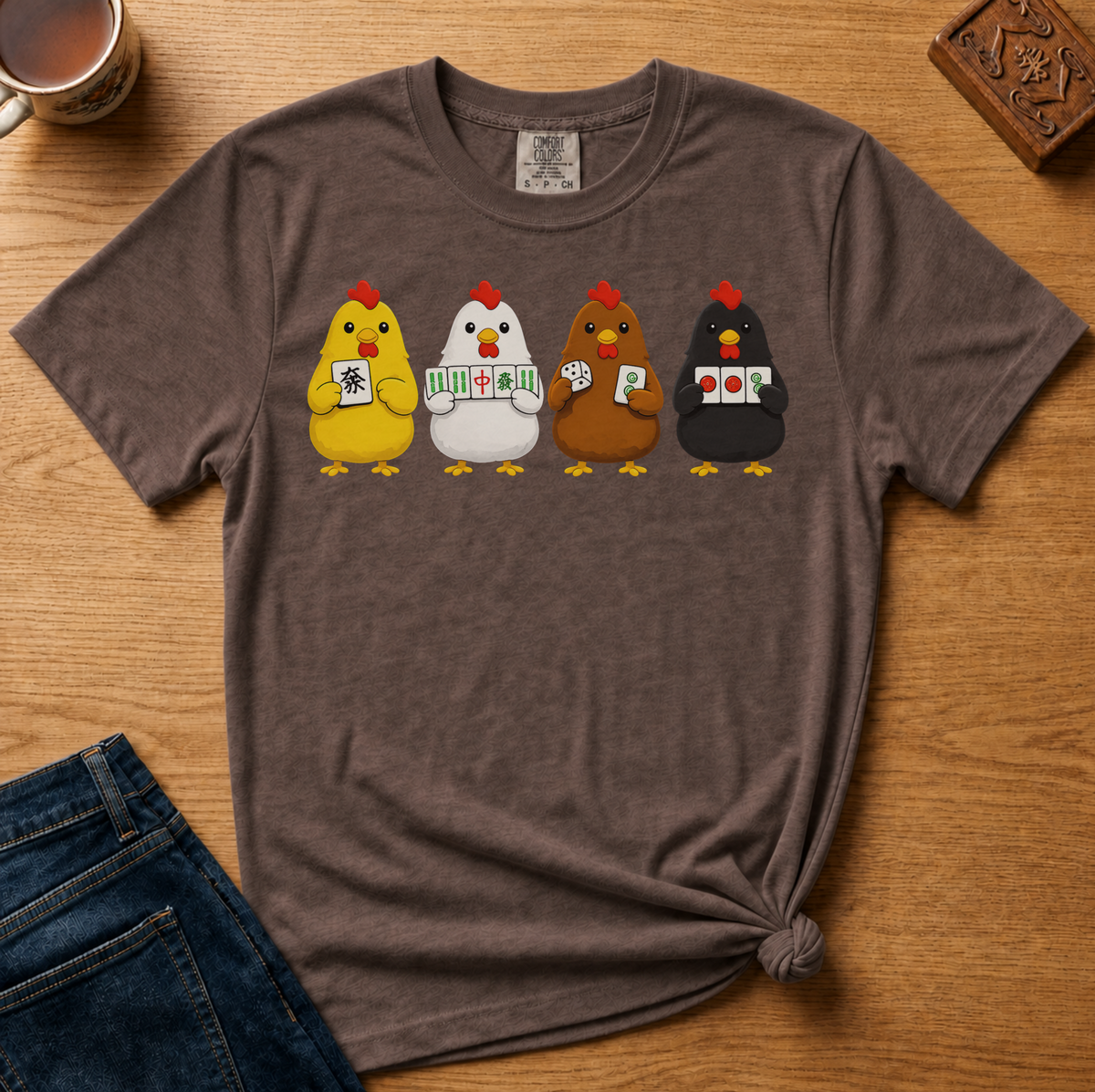Mahjong Chickens Shirt in Pepper - four cartoon hens holding mahjong tiles on a dark grey Comfort Colors 1717 tee, flat lay