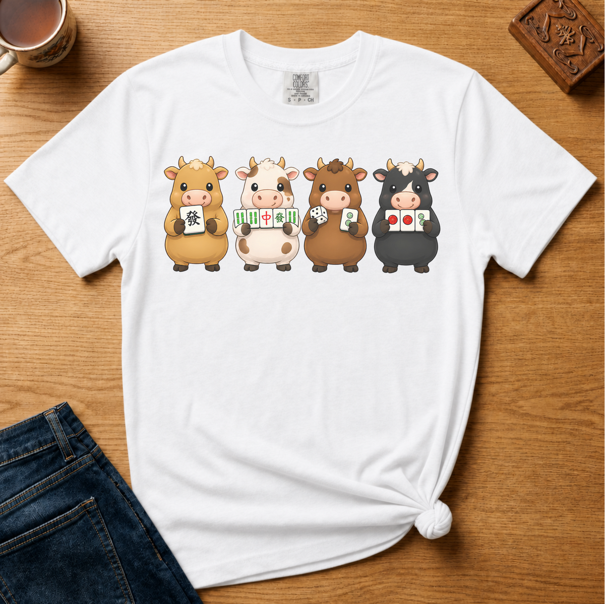 Mahjong Cows Shirt in White - four cartoon cows holding mahjong tiles on a white Comfort Colors 1717 tee, flat lay
