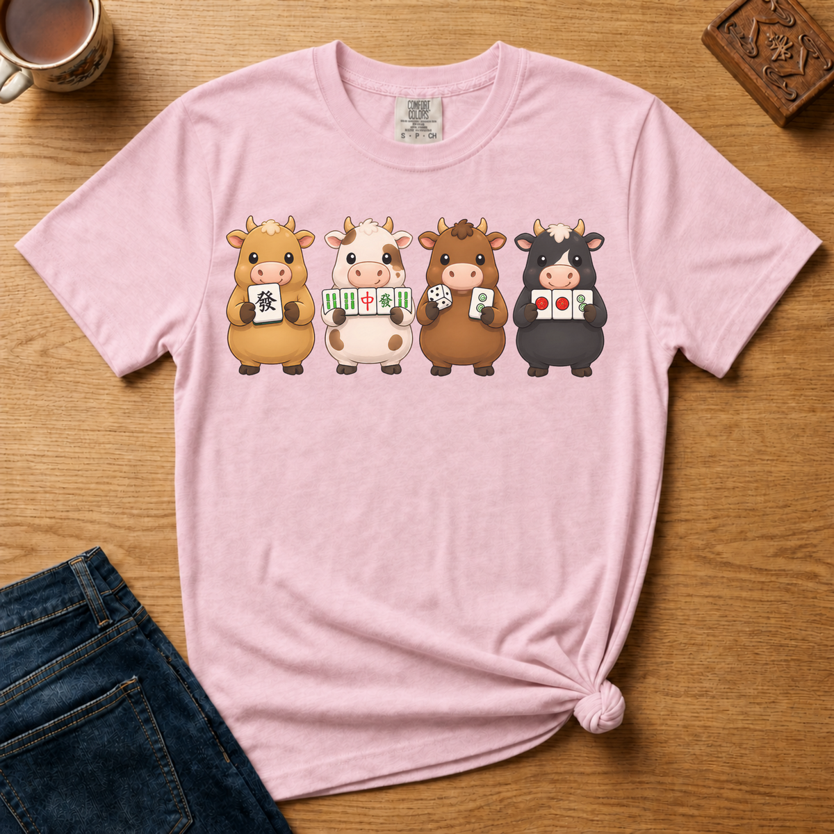 Mahjong Cows Shirt in Ivory - four cartoon cows holding mahjong tiles on an ivory Comfort Colors 1717 tee, flat lay