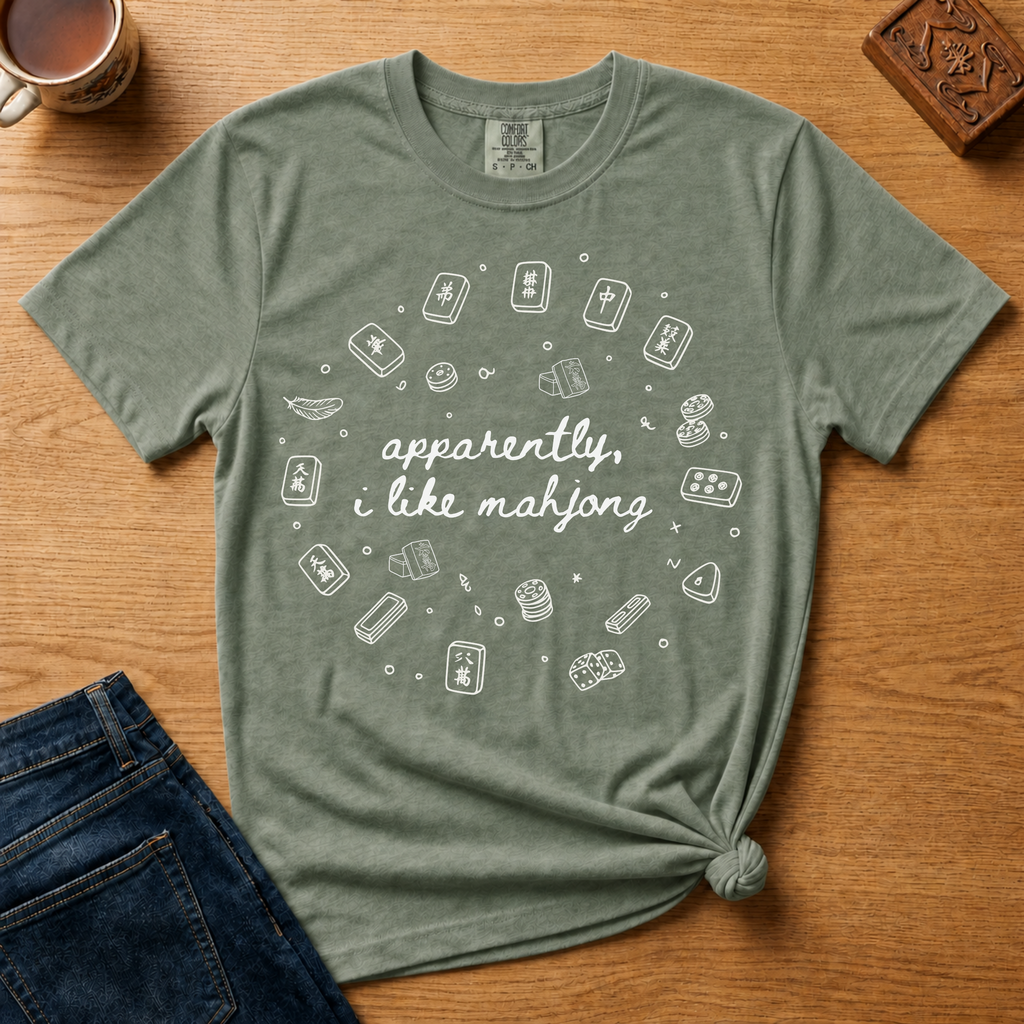 Apparently I Like Mahjong Shirt in Moss - hand-lettered script with line-art tile doodles on a green Comfort Colors 1717 tee, flat lay