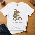 Off To Play Mahjong Shirt in Blossom - storybook frog in a polka-dot hat riding a bicycle with mahjong tiles on a pink Comfort Colors 1717 tee, flat lay