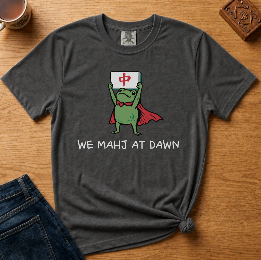 We Mahj At Dawn Shirt in Black - superhero frog in a red cape holding a red dragon tile overhead on a black Comfort Colors 1717 tee, flat lay
