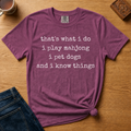 Pet Dogs And Play Mahjong Shirt in Berry - white typewriter text 'that's what i do, i play mahjong, i pet dogs, and i know things' on a berry Comfort Colors 1717 tee, flat lay