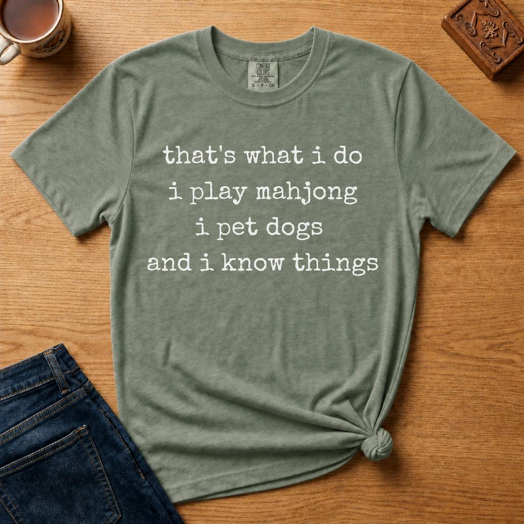Pet Dogs And Play Mahjong Shirt in Espresso - white typewriter text 'that's what i do, i play mahjong, i pet dogs, and i know things' on a brown Comfort Colors 1717 tee, flat lay