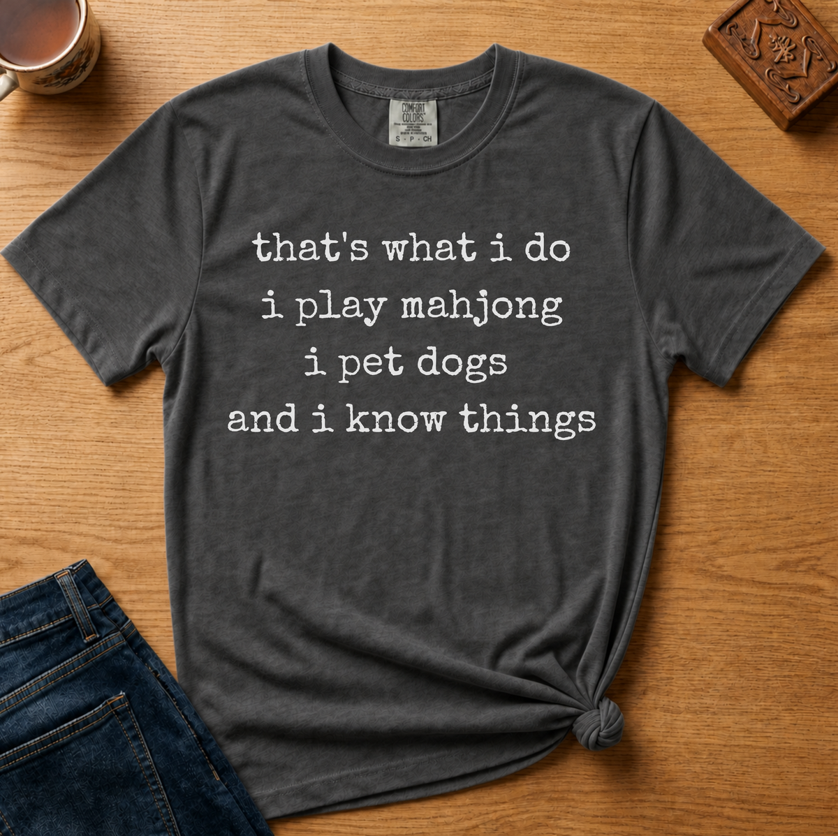 Pet Dogs And Play Mahjong Shirt in Black - white typewriter text 'that's what i do, i play mahjong, i pet dogs, and i know things' on a black Comfort Colors 1717 tee, flat lay