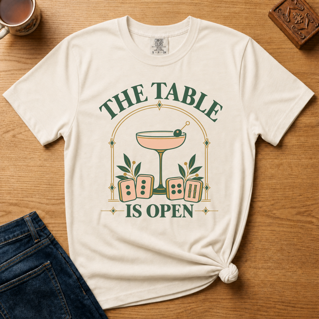 The Table Is Open Shirt in Ivory - green serif lettering, gold deco arch, cocktail coupe and peach mahjong tiles