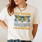 Keep Talking, I'm Counting owl mahjong shirt in Violet, styled flat lay on a wooden table with coffee.