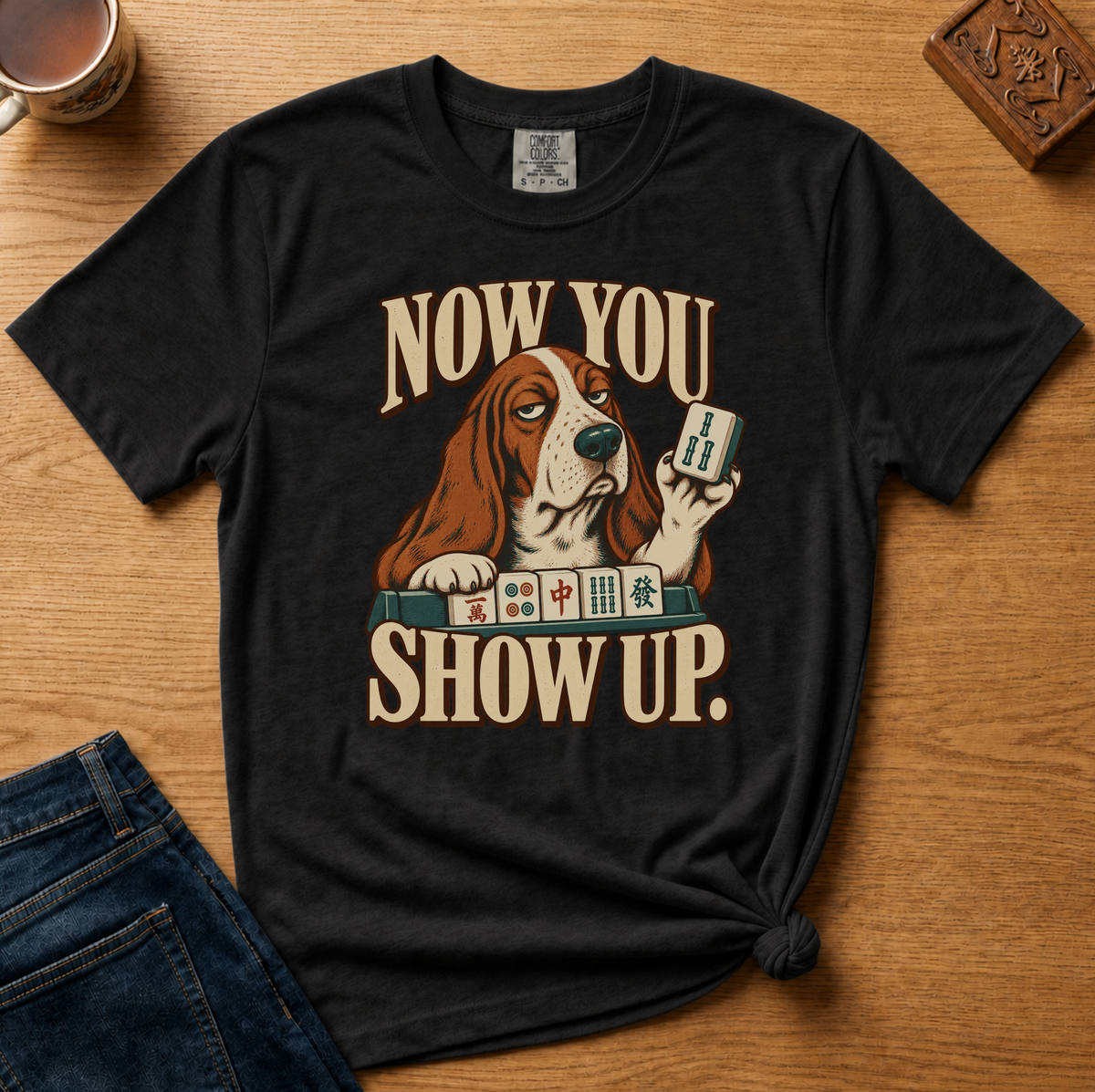 Close-up of the Now You Show Up basset hound design on a White Comfort Colors t-shirt.