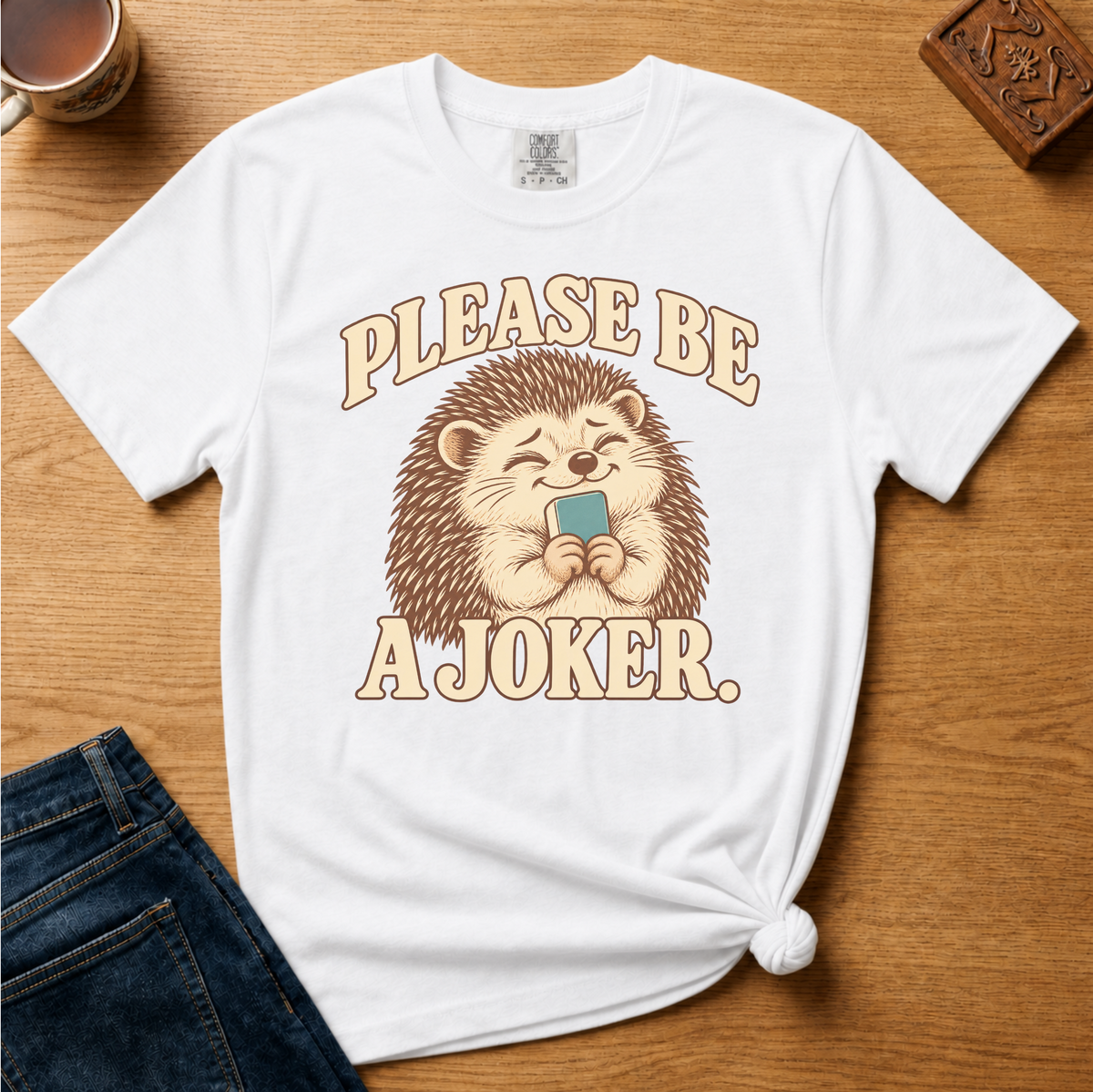 Close-up of the Please Be A Joker hedgehog design on a Moss Comfort Colors t-shirt.