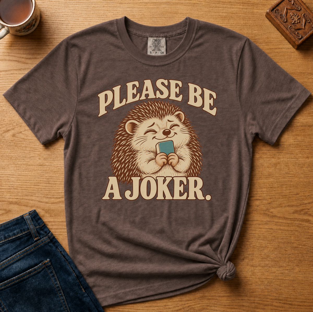 Close-up of the Please Be A Joker hedgehog design on a Blossom Comfort Colors t-shirt.