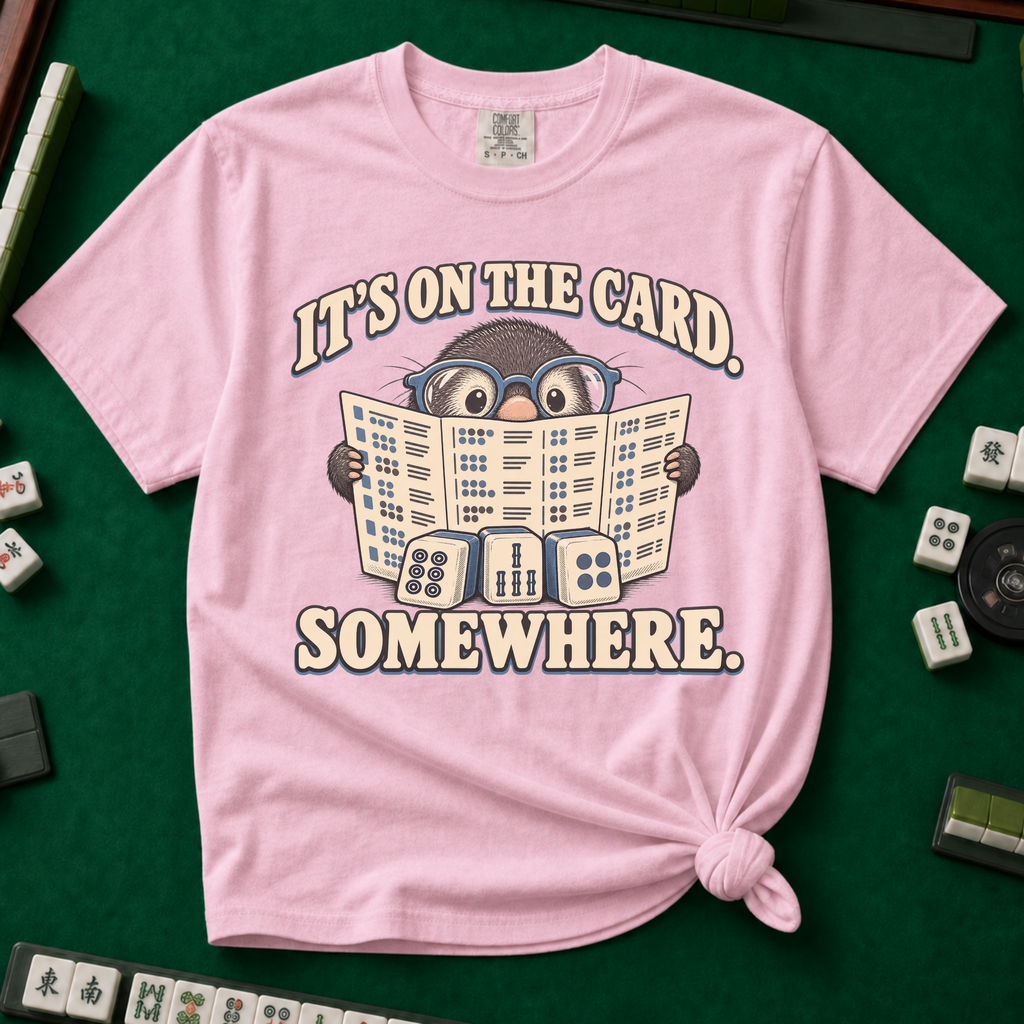 It's On The Card Somewhere mahjong shirt in Moss — a wide-eyed mole in oversized glasses peeking over the open mahjong card, three tiles below, with the words IT'S ON THE CARD. SOMEWHERE.
