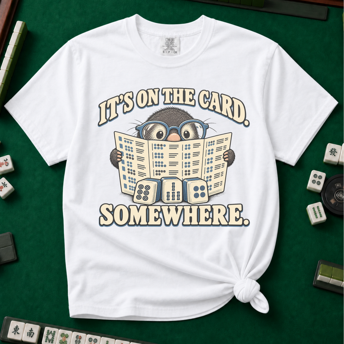It's On The Card Somewhere mahjong shirt in Berry — a wide-eyed mole in oversized glasses peeking over the open mahjong card, three tiles below, with the words IT'S ON THE CARD. SOMEWHERE.