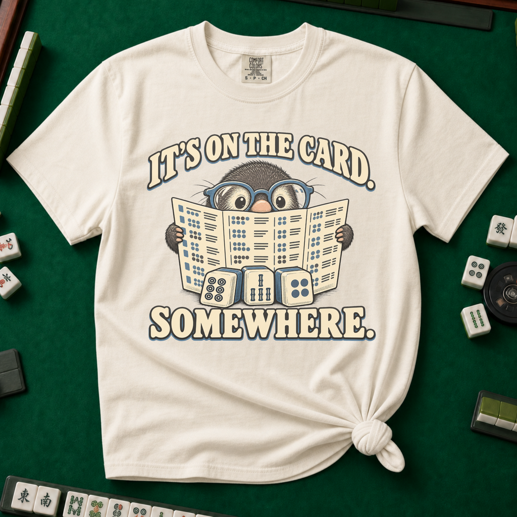 Close-up of the It's On The Card Somewhere design on White — the mole in glasses gripping the open mahjong card, its pages printed with rows of tile patterns.