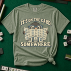 It's On The Card Somewhere mahjong shirt in Blossom — a wide-eyed mole in oversized glasses peeking over the open mahjong card, three tiles below, with the words IT'S ON THE CARD. SOMEWHERE.