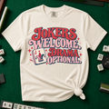 Jokers Welcome Drama Optional T-Shirt in Ivory - tee laid flat on a green mahjong mat with scattered tiles, printed with the words Jokers Welcome Drama Optional in retro bubble lettering with a joker tile