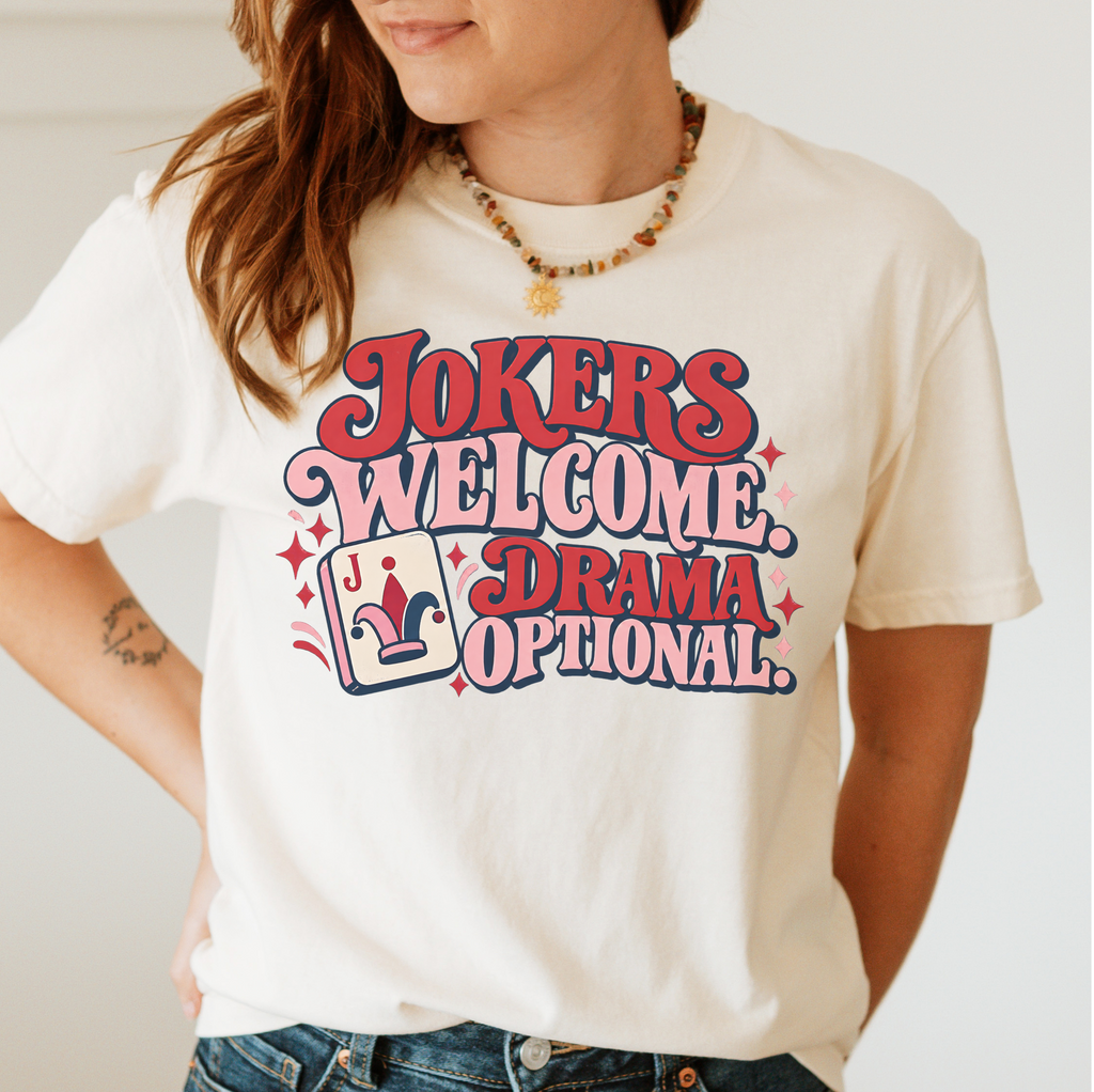 Jokers Welcome Drama Optional T-Shirt in Moss - knotted tee on a green mahjong mat with scattered tiles, printed with the words Jokers Welcome Drama Optional in retro bubble lettering with a joker tile