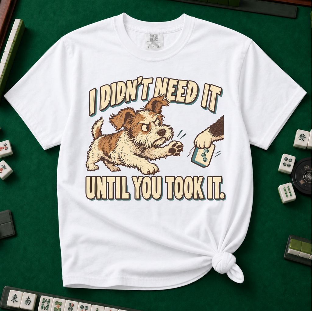 I Didn't Need It Until You Took It T-Shirt in White - knotted tee on a green mahjong mat with scattered tiles, printed with a scruffy puppy lunging for a tile as another paw takes it away, and the words I Didn't Need It Until You Took It