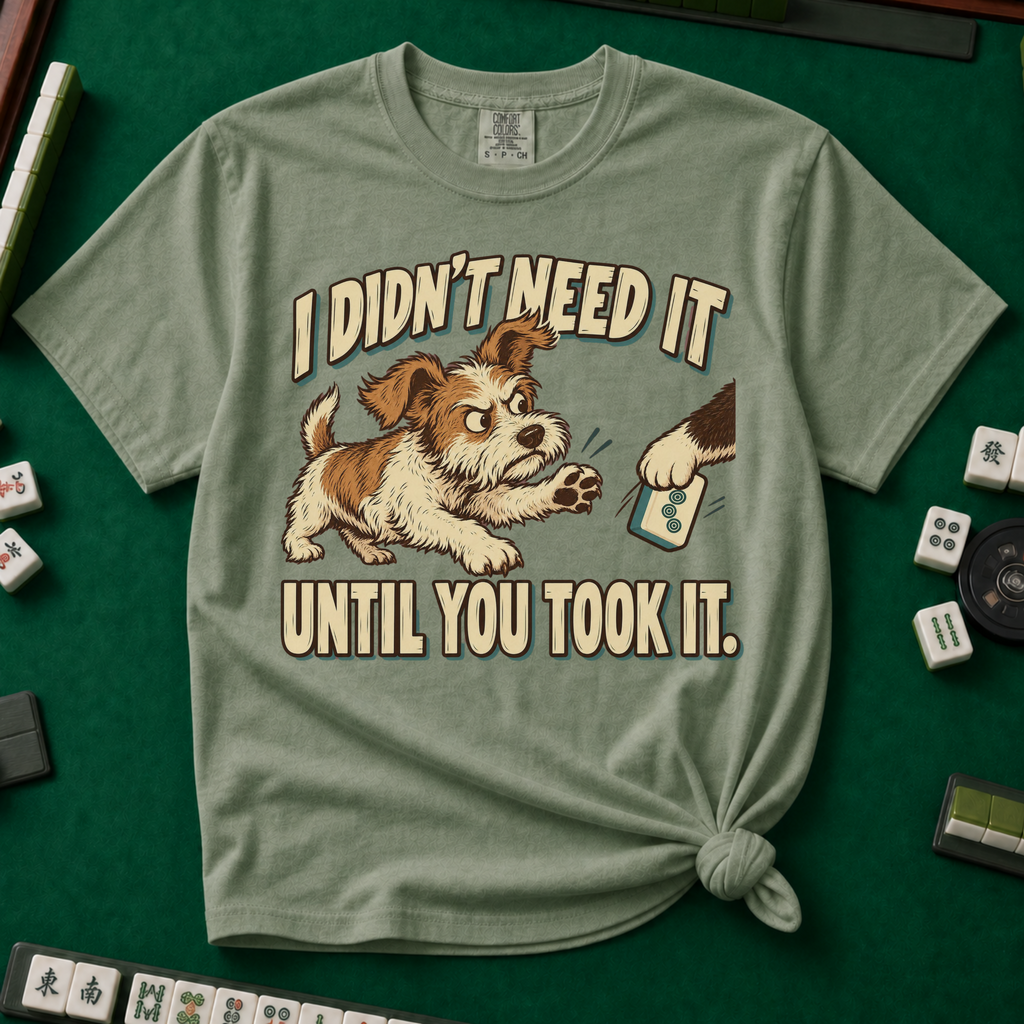 I Didn't Need It Until You Took It T-Shirt in Moss - knotted tee on a green mahjong mat with scattered tiles, printed with a scruffy puppy lunging for a tile as another paw takes it away, and the words I Didn't Need It Until You Took It