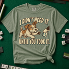 I Didn't Need It Until You Took It T-Shirt in Moss - knotted tee on a green mahjong mat with scattered tiles, printed with a scruffy puppy lunging for a tile as another paw takes it away, and the words I Didn't Need It Until You Took It