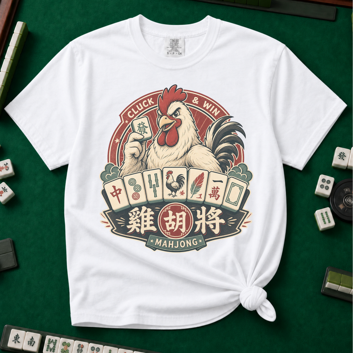 Cluck And Win Mahjong Rooster T-Shirt in White - knotted tee on a green mahjong mat with scattered tiles, printed with a rooster holding a green dragon tile above a fan of mahjong tiles in a red Cluck and Win badge