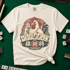 Cluck And Win Mahjong Rooster T-Shirt in Ivory - knotted tee on a green mahjong mat with scattered tiles, printed with a rooster holding a green dragon tile above a fan of mahjong tiles in a red Cluck and Win badge