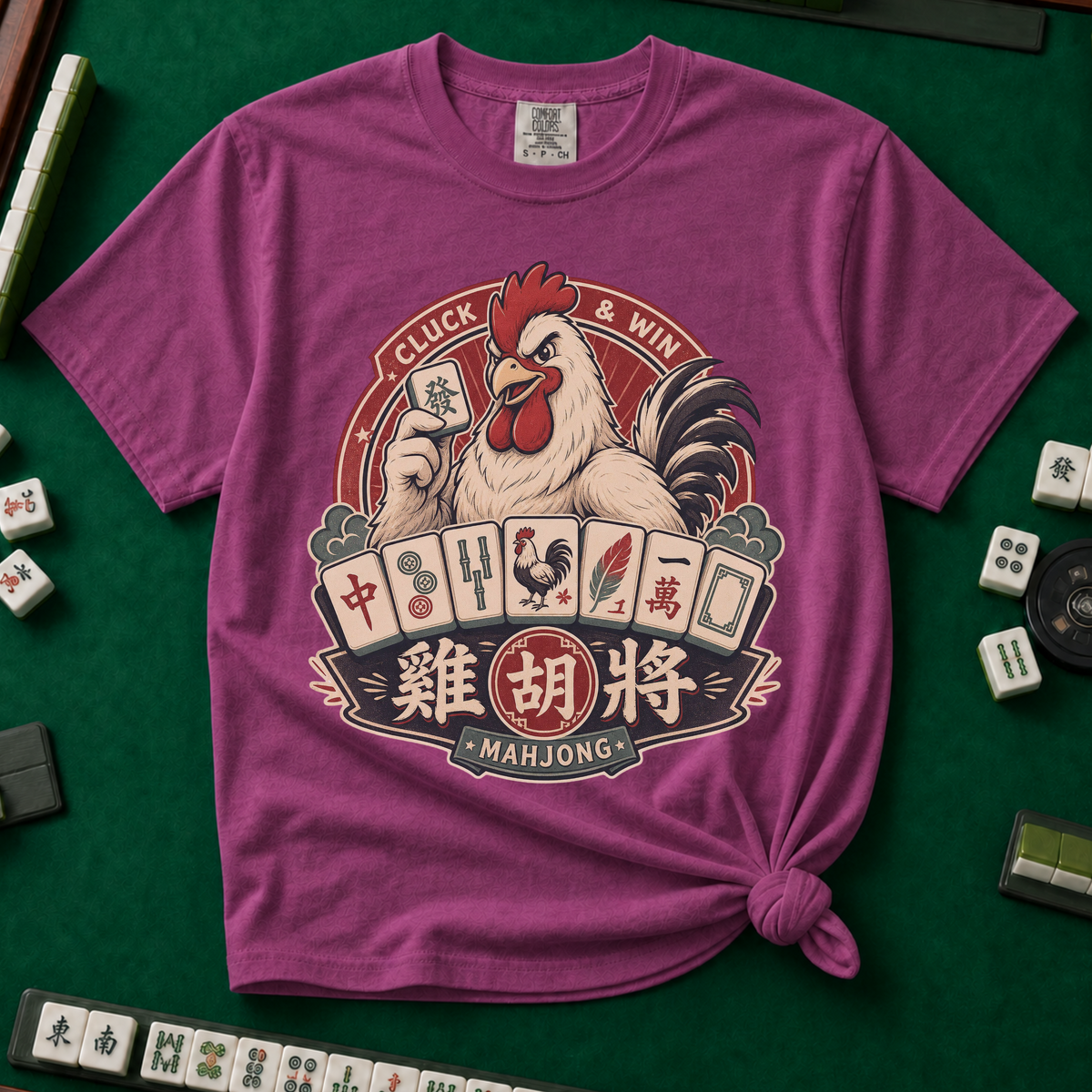 Cluck And Win Mahjong Rooster T-Shirt in Berry - knotted tee on a green mahjong mat with scattered tiles, printed with a rooster holding a green dragon tile above a fan of mahjong tiles in a red Cluck and Win badge