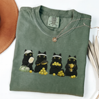 Four black cats with pickleball paddles, balls and a trophy printed on a Moss Comfort Colors T-shirt.