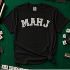 MAHJ Varsity T-Shirt in Black, knotted flat lay on a green mahjong mat - "MAHJ" in big white varsity arch letters with a stitched letterman look