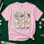 Mahjong Chicken Tiles T-Shirt in Blossom, knotted flat lay on a green mahjong mat - a 3x3 grid of mahjong tiles, each starring a cartoon chicken with its own personality - varsity jacket, karate gi, cape, beanie, headphones, bookworm glasses, cherry blossom, pool floatie and skateboard