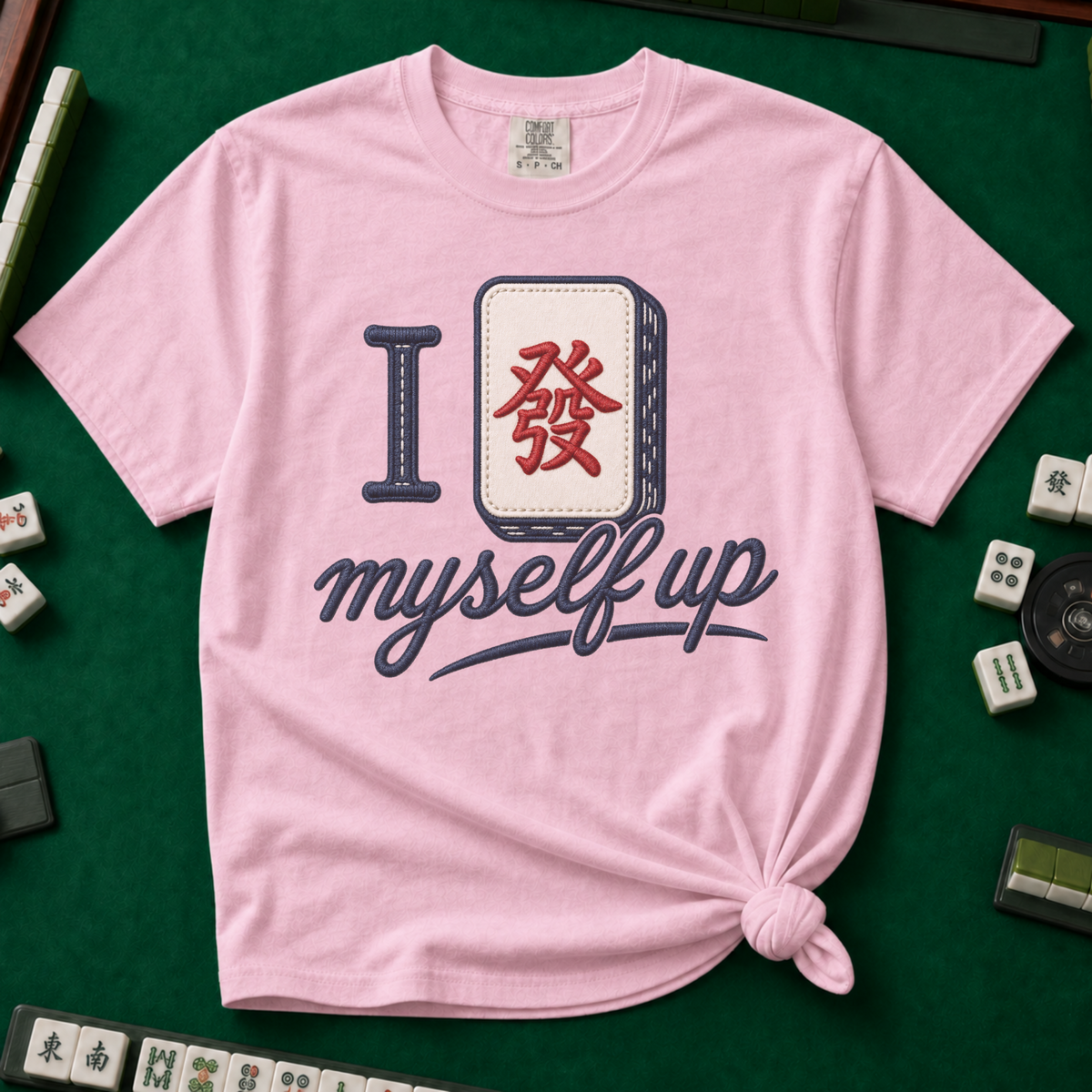 I Set Myself Up T-Shirt in Blossom, knotted flat lay on a green mahjong mat - a stitched-look varsity rebus - a navy letter I beside a cream fa dragon tile with the red character, over "myself up" in navy script