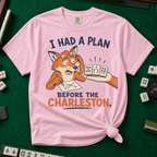I Had A Plan Before The Charleston T-Shirt in Blossom, knotted flat lay on a green mahjong mat - a stressed cartoon fox with glasses and a strategy sketch being handed three mahjong tiles, with the words "I HAD A PLAN BEFORE THE CHARLESTON."