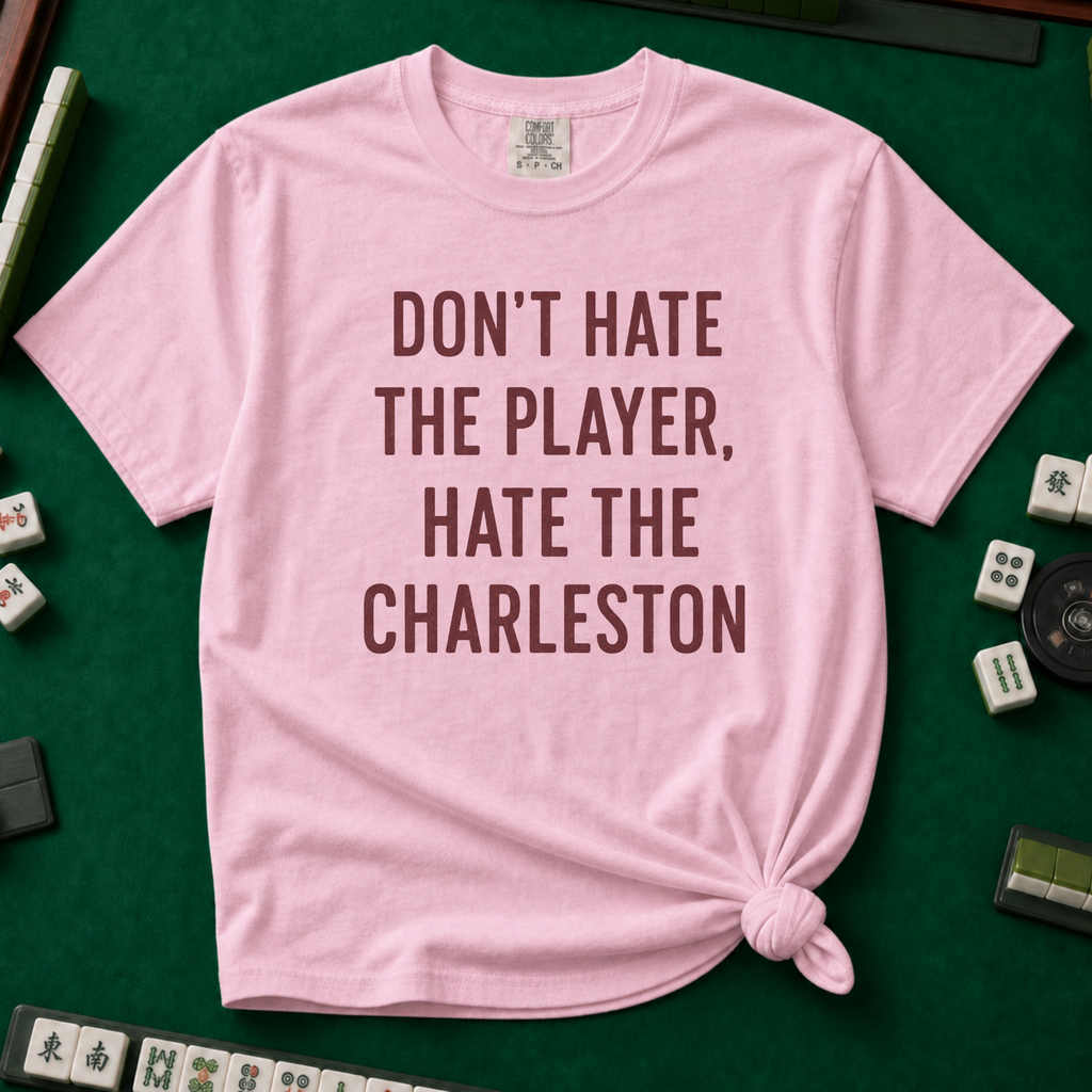 Don't Hate The Player Hate The Charleston T-Shirt in Blossom, knotted flat lay on a green mahjong mat - "DON'T HATE THE PLAYER, HATE THE CHARLESTON" in deep burgundy block letters