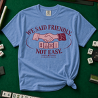 We Said Friendly Not Easy T-Shirt in Blue Jean, knotted flat lay on a green mahjong mat - a burgundy and pink club badge with a handshake over four mahjong tiles and the words "WE SAID FRIENDLY. NOT EASY. MAHJONG CLUB."