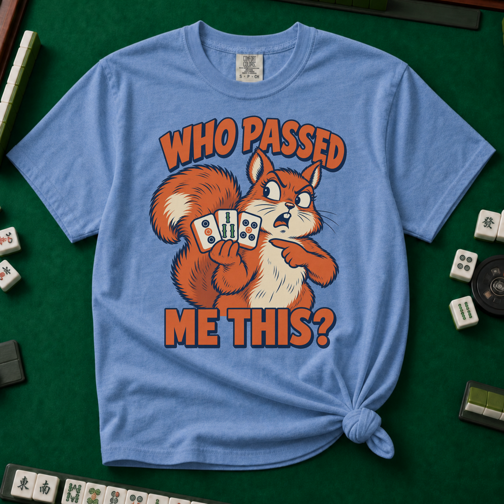 Who Passed Me This T-Shirt in Blue Jean, knotted flat lay on a green mahjong mat - retro orange squirrel holding three mahjong tiles, pointing an accusing paw - "WHO PASSED ME THIS?" in bold orange letters