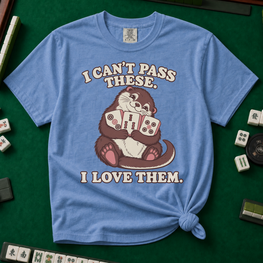 I Can't Pass These I Love Them T-Shirt in Blue Jean, knotted flat lay on a green mahjong mat - lovestruck otter hugging three mahjong tiles to her chest - "I CAN'T PASS THESE. I LOVE THEM." in cream retro letters