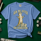 Ask Me After The Charleston T-Shirt in Blue Jean, knotted flat lay on a green mahjong mat - shrugging meerkat standing beside three mahjong tiles - "ASK ME AFTER THE CHARLESTON." in cream collegiate letters