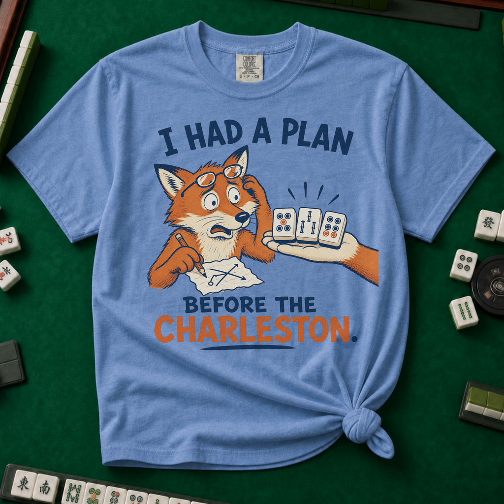 I Had A Plan Before The Charleston T-Shirt in Blue Jean, knotted flat lay on a green mahjong mat - a stressed cartoon fox with glasses and a strategy sketch being handed three mahjong tiles, with the words "I HAD A PLAN BEFORE THE CHARLESTON."