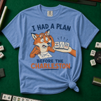 I Had A Plan Before The Charleston T-Shirt in Blue Jean, knotted flat lay on a green mahjong mat - a stressed cartoon fox with glasses and a strategy sketch being handed three mahjong tiles, with the words "I HAD A PLAN BEFORE THE CHARLESTON."