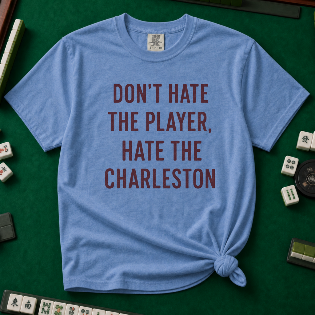 Don't Hate The Player Hate The Charleston T-Shirt in Blue Jean, knotted flat lay on a green mahjong mat - "DON'T HATE THE PLAYER, HATE THE CHARLESTON" in deep burgundy block letters