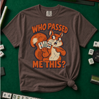 Who Passed Me This T-Shirt in Espresso, knotted flat lay on a green mahjong mat - retro orange squirrel holding three mahjong tiles, pointing an accusing paw - "WHO PASSED ME THIS?" in bold orange letters