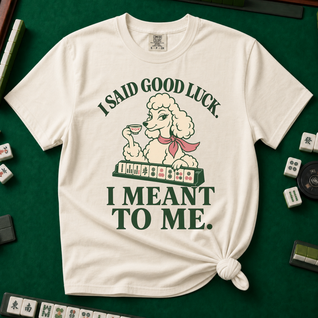 I Said Good Luck T-Shirt in Ivory - knotted tee flat lay on a green mahjong mat with tiles, printed with a cream poodle in a pink scarf holding a teacup behind a rack of mahjong tiles, with the words I SAID GOOD LUCK. I MEANT TO ME.