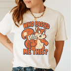 Woman wearing the Who Passed Me This T-Shirt in Ivory - retro orange squirrel holding three mahjong tiles, pointing an accusing paw - "WHO PASSED ME THIS?" in bold orange letters