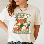 Woman wearing the I'm Trying To Look Disappointed T-Shirt in Ivory - smug retro fox holding up a joker tile, hiding a grin behind one paw, tile rack in front - "I'M TRYING TO LOOK DISAPPOINTED." in cream collegiate letters
