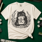 Linocut Tile Cat T-Shirt in Ivory, knotted flat lay on a green mahjong mat - a linocut-style black cat hugging a Green Dragon mahjong tile inside a wreath of wheat, daisies and lavender
