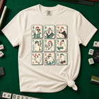 Mahjong Chicken Tiles T-Shirt in Ivory, knotted flat lay on a green mahjong mat - a 3x3 grid of mahjong tiles, each starring a cartoon chicken with its own personality - varsity jacket, karate gi, cape, beanie, headphones, bookworm glasses, cherry blossom, pool floatie and skateboard