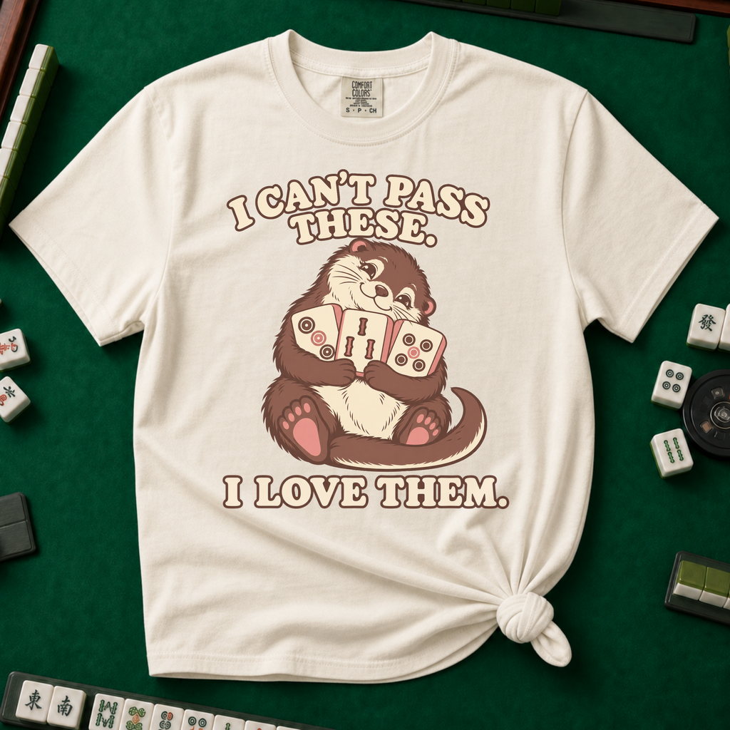 I Can't Pass These I Love Them T-Shirt in Ivory, knotted flat lay on a green mahjong mat - lovestruck otter hugging three mahjong tiles to her chest - "I CAN'T PASS THESE. I LOVE THEM." in cream retro letters