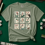 Mahjong Chicken Tiles T-Shirt in Moss, knotted flat lay on a green mahjong mat - a 3x3 grid of mahjong tiles, each starring a cartoon chicken with its own personality - varsity jacket, karate gi, cape, beanie, headphones, bookworm glasses, cherry blossom, pool floatie and skateboard