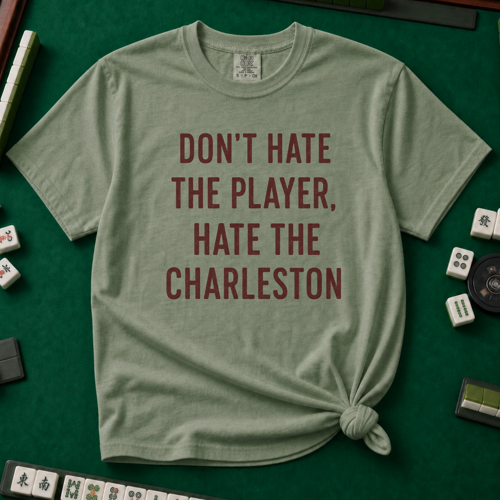 Don't Hate The Player Hate The Charleston T-Shirt in Moss, knotted flat lay on a green mahjong mat - "DON'T HATE THE PLAYER, HATE THE CHARLESTON" in deep burgundy block letters